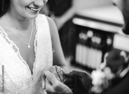 Groom putting on the wedding ring on his bride photo