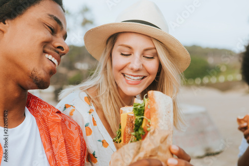 Couple dating and eating sandwiches at a beach picnic