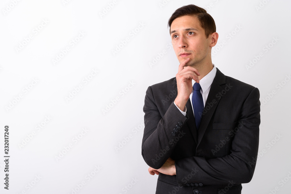 Studio shot of young handsome businessman thinking while looking Studio shot of young handsome businessman thinking while looking