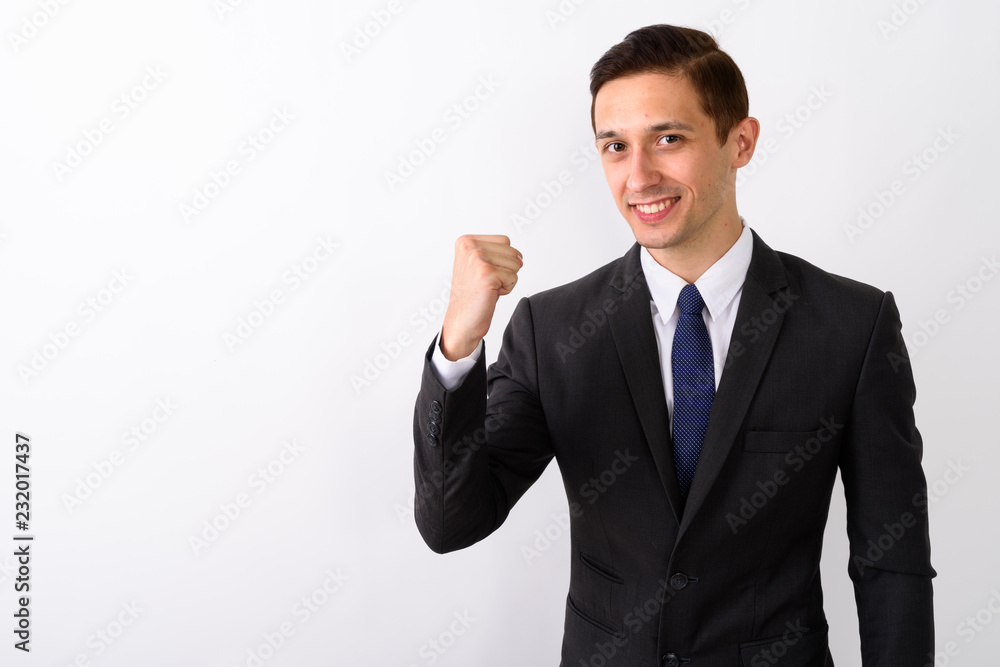 Studio shot of young happy businessman smiling while looking mot Studio shot of young happy businessman smiling while looking mot
