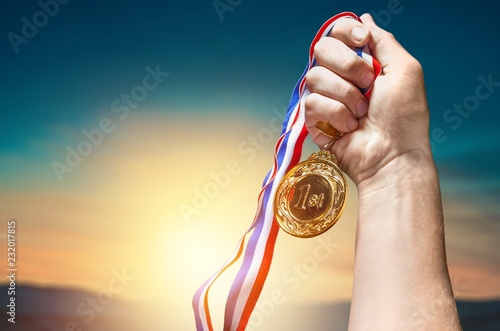 Gold medal with ribbon in hand on background