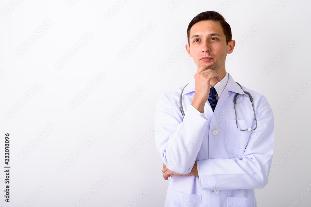 Studio shot of young handsome man doctor thinking against white Studio shot of young handsome man doctor thinking against white