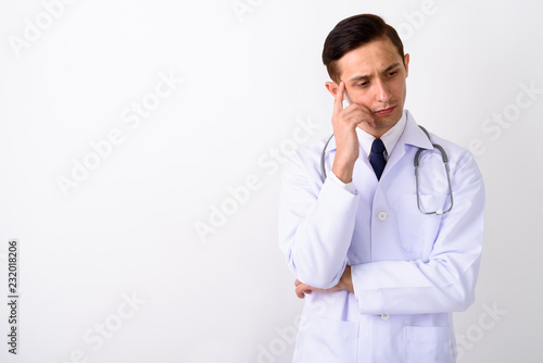 Studio shot of young handsome man doctor thinking with finger on