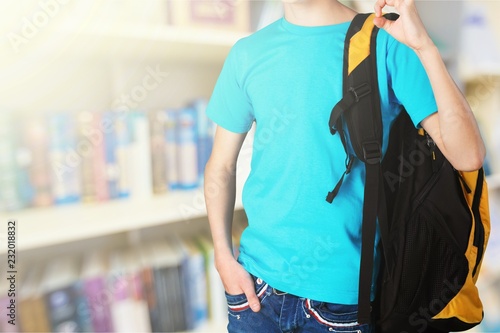 Teen boy with schoolbag and book on background