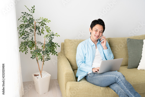 パソコンを見ながら、電話をする若い男性