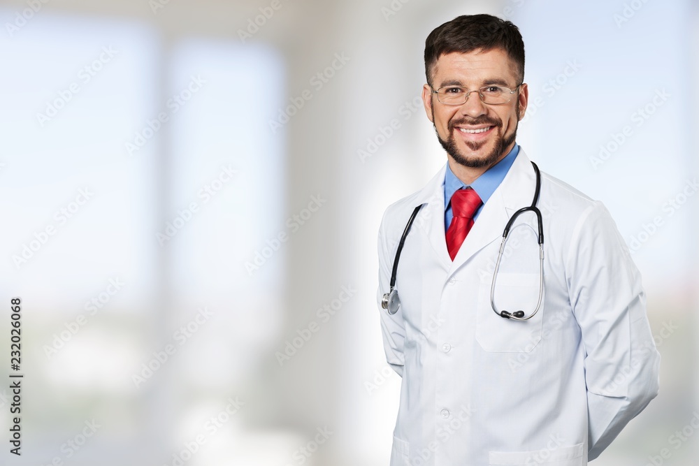 Handsome young male doctor with blurred hospital interior on