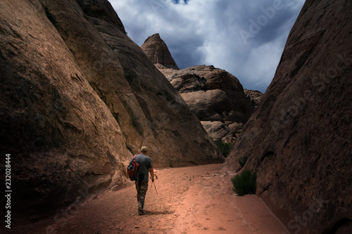 Traveler with a backpack goes through the canyon. Clouds. Capitol Gorge Trail, Capitol Reef National Park, Utah, USA