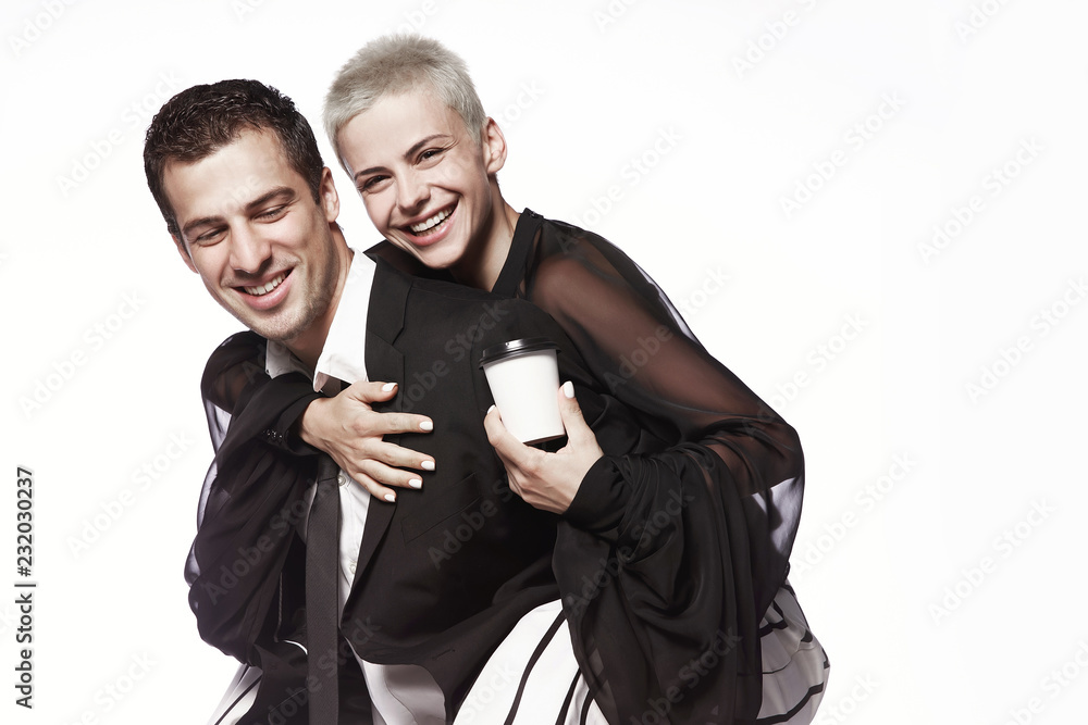 A girl with a short haircut sits on the guy's back, with coffee cups on a white background. Coffee to go. Advertising. A girl with a short haircut sits on the guy's back, with coffee cups on a white background. Coffee to go. Advertising.