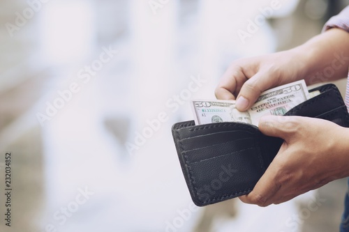 close up Businessman Person holding an wallet in the hands of an man take money out of pocket. finance concept 