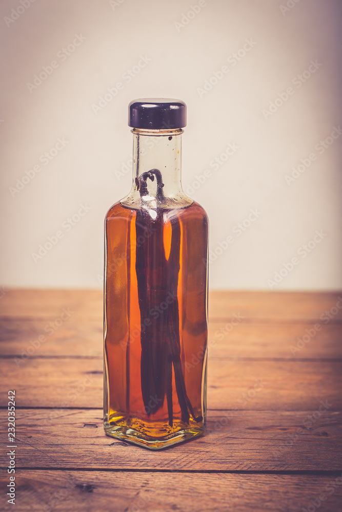 Bottle of homemade vanilla essence on wooden background
