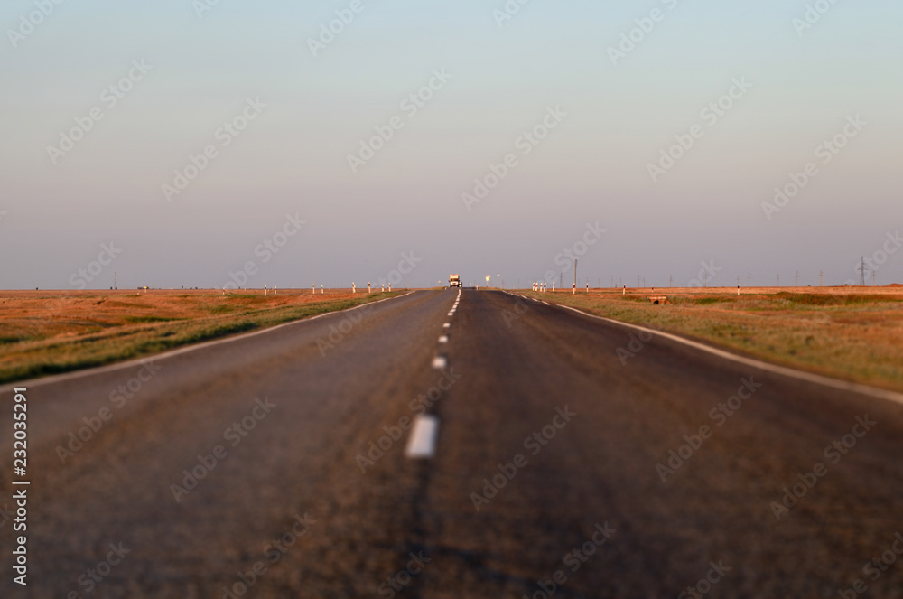 An empty asphalt road in the steppe at sunset. The Astrakhan region. Russia. Tilt-shift effect.