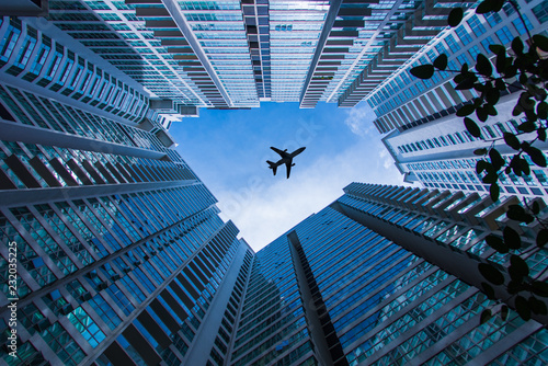 The plane is flying over skyscrapers. Modern architecture residential or office buildings down top view on sky and aircraft flying over. Developed Malaysian capital city.