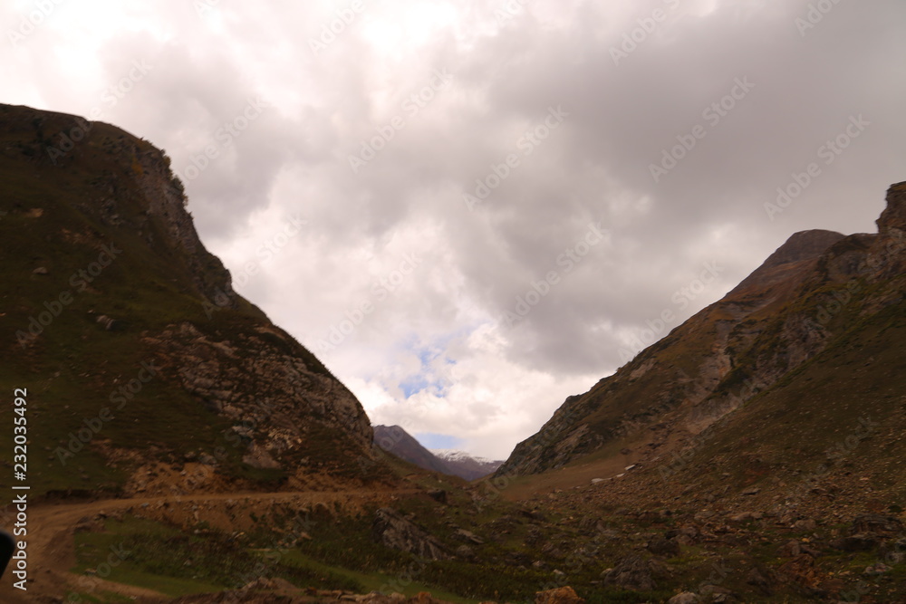 View of beautiful mountains and track passing through under dark clouds