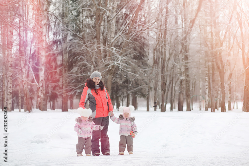 Obraz premium Children walk in the park in winter. Winter forest a family with children on a walk. A cold winter day is a family walk.