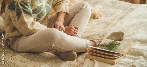 Cozy home. Beautiful girl is reading a book on the bed. Good morning with tea. Pretty young girl relaxing. The concept of reading