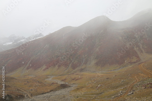 Mountains in autumn with brown and reddish grass under cloudy sky © Safeer