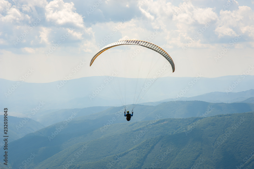 Paraglider fly over a mountain valley on a sunny summer day. Paragliding in the Carpathians in the summer. Paraglider fly over a mountain valley on a sunny summer day. Paragliding in the Carpathians in the summer.