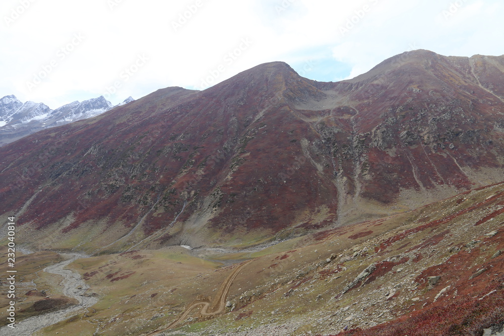 Mountains in autumn with brown and reddish grass under cloudy sky Mountains in autumn with brown and reddish grass under cloudy sky