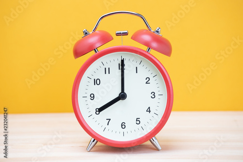 vintage retro alarm clock eight minutes to twelve time o'clock on table wood with yellow background. 