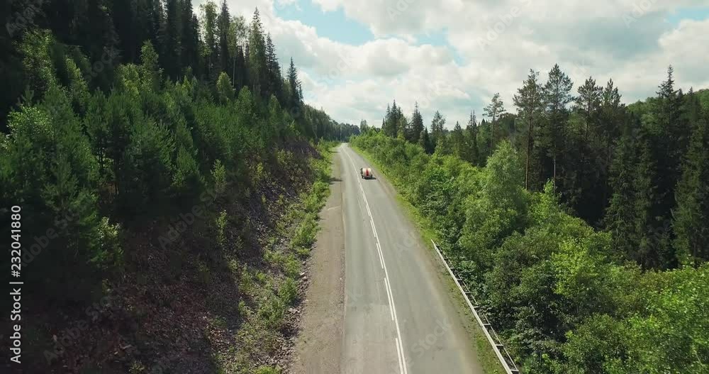 One Black Car with Funny Tear Trailer driving on Winding Freeway in Forest Mountains - Aerial Drone View One Black Car with Funny Tear Trailer driving on Winding Freeway in Forest Mountains - Aerial Drone View