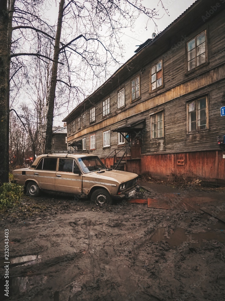 Abandoned place, mud all around, old car stuck in the mud, wooden house almost collapsed Abandoned place, mud all around, old car stuck in the mud, wooden house almost collapsed