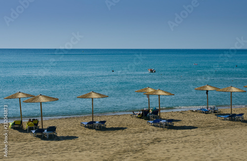 Mediterranean landscape with beach umbrellas and sunbeds in the background blue sky