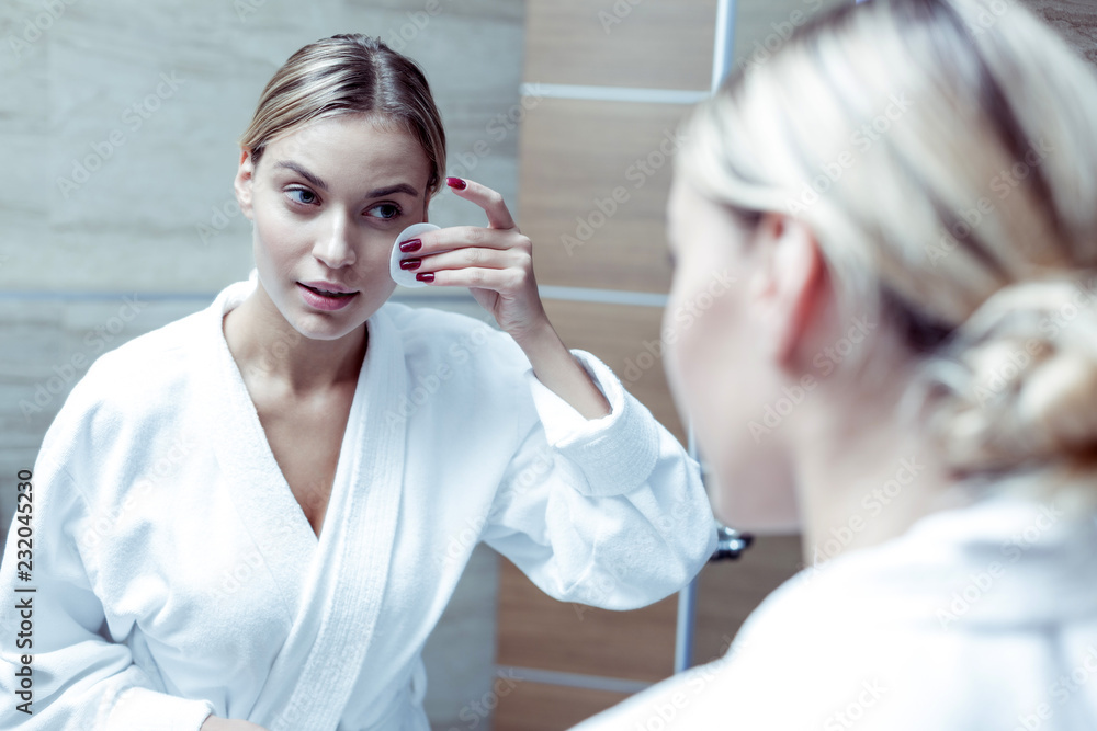 Beaming woman wearing white bathrobe cleaning her skin before sleep Beaming woman wearing white bathrobe cleaning her skin before sleep