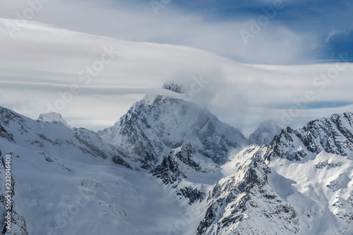 Snow covered Mt. Aksaut in clouds. Dombay ski resort, Western Caucasus, Russia.