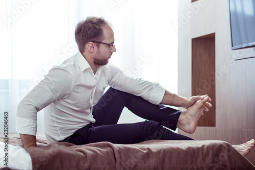 Tired businessman making feet massage after all day working