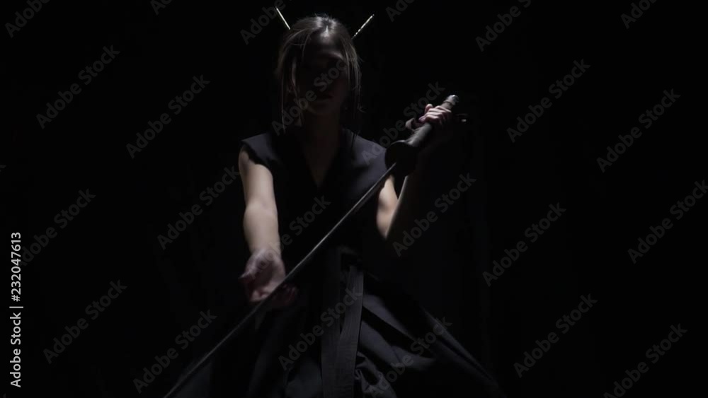 Dangerous asian lady points with katana from the dark, slow motion Dangerous asian lady points with katana from the dark, slow motion