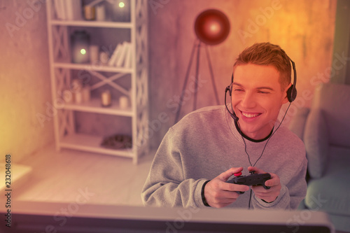 Wall Mural Enthusiastic young fellow using gamepad for videogame