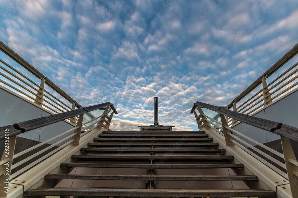 Abstract picture of a wooden staircase going up to the regular blue clouds shape sky Abstract picture of a wooden staircase going up to the regular blue clouds shape sky