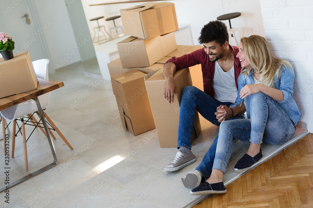 Young couple unpacking cardboard boxes at new home moving in concept Young couple unpacking cardboard boxes at new home moving in concept