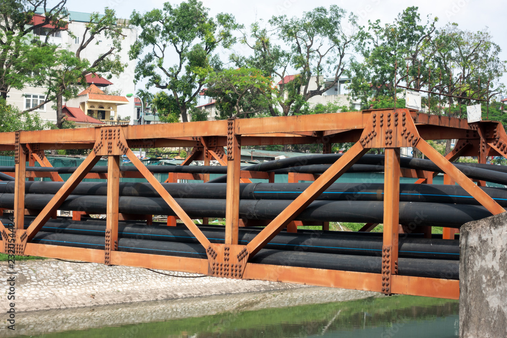 Black electric wire stacked on metal rail crossing river in city