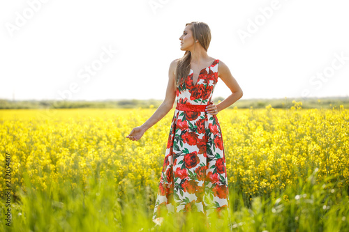 Blode girl posing in red dress in yellow field