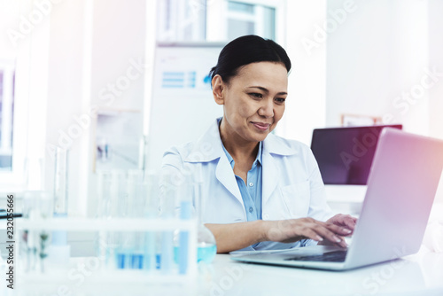 Joyful positive woman sitting in front of the laptop