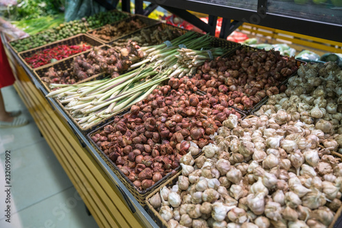 Vegetables on shelves in supermarket with fresh chilli, dry onion, dry ginger, dry citronella...