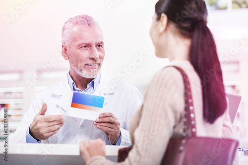Confident worker of the pharmacy offering new medication to a woman