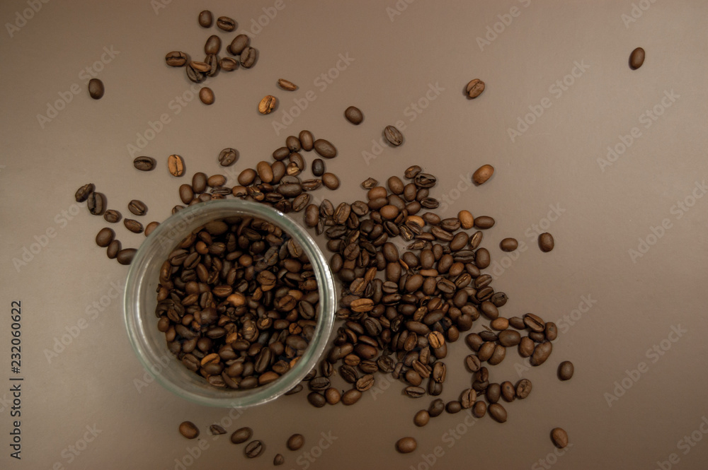 glass jar with coffee and coffee beans scattered on the table glass jar with coffee and coffee beans scattered on the table