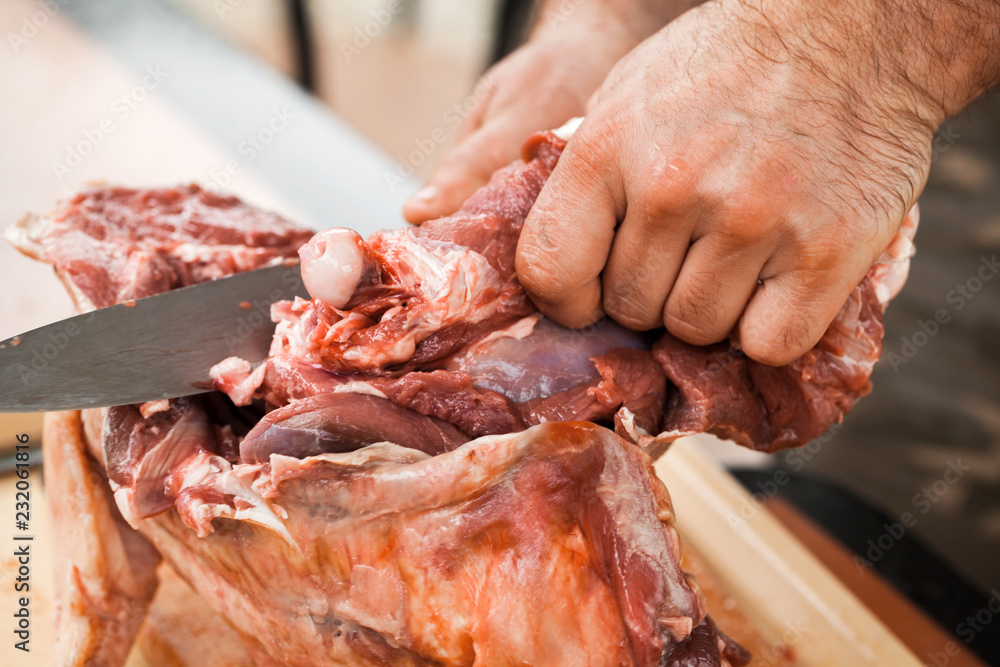 Raw lamb cutting, cook hands with knife