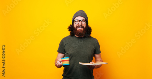 Bearded hipster man holding a book and drinking coffee © Vulp