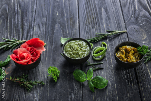 Tasty sauces with marinated ginger and herbs on wooden table