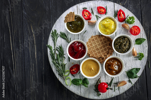 Different tasty sauces in bowls with waffles on wooden table