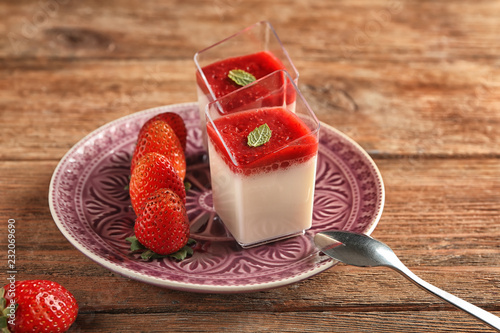 Glasses with tasty strawberry panna cotta on plate