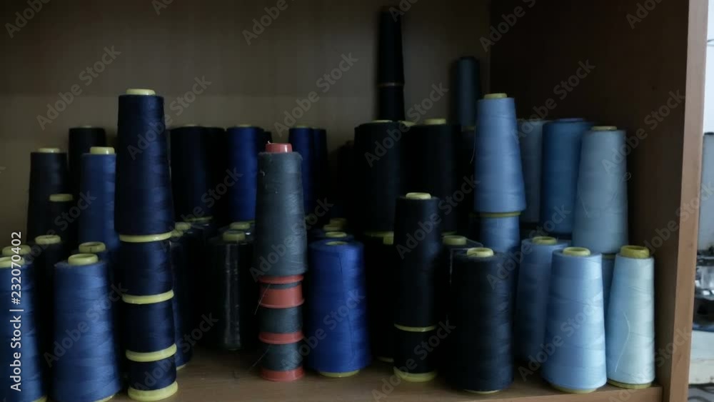 a lot of coils with blue threads. Bobbins are stacked in rows, one on the other. a lot of coils with blue threads. Bobbins are stacked in rows, one on the other.
