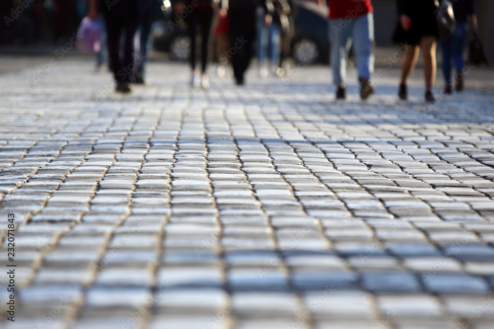 Fototapeta premium people cross the road at a pedestrian crossing on the pavement in a blurred focus