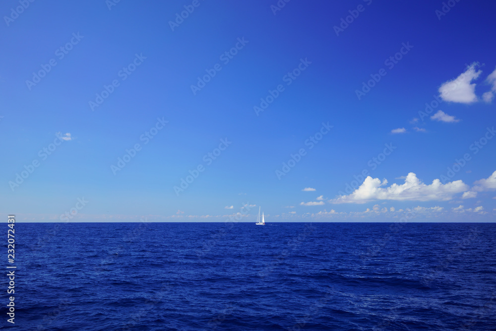 A white sailing yacht in the open waters of the Mediterranean Sea. Maritime landscape with the deep blue color of the ocean, off the coast of northern Majorca, Spain.