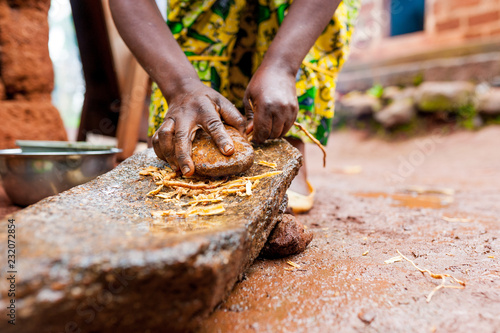 close up of african woman hands making traditional spices with homemade mortar in village
