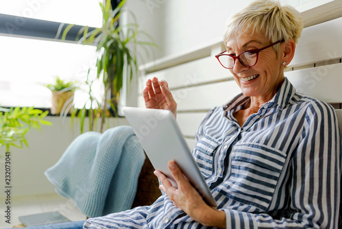 Smiling beautiful senior woman using digital tablet at home
