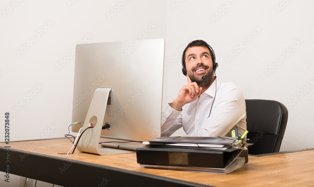 Telemarketer man in a office thinking an idea while looking up Telemarketer man in a office thinking an idea while looking up
